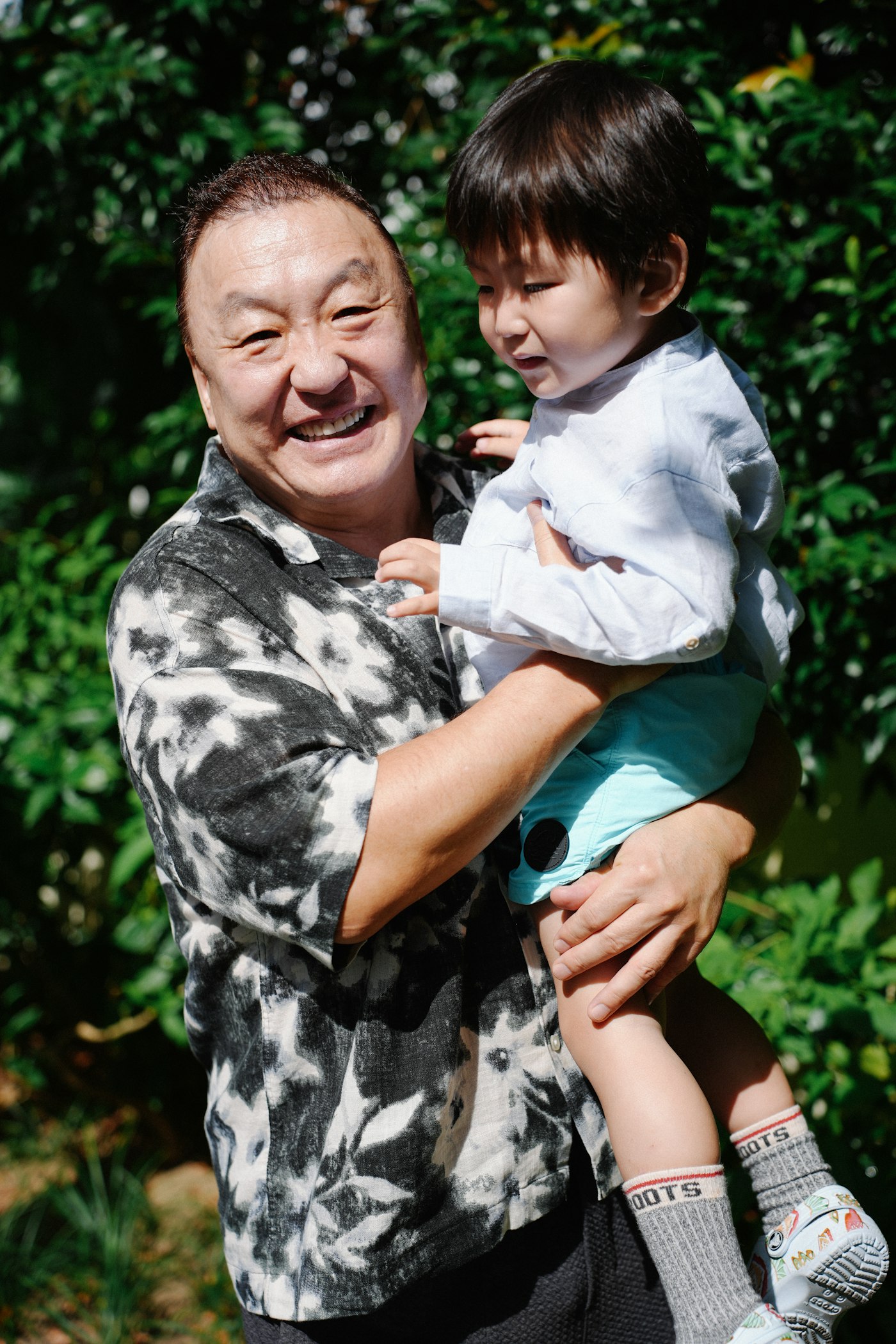 Grandfather joyfully holding grandchild outdoors